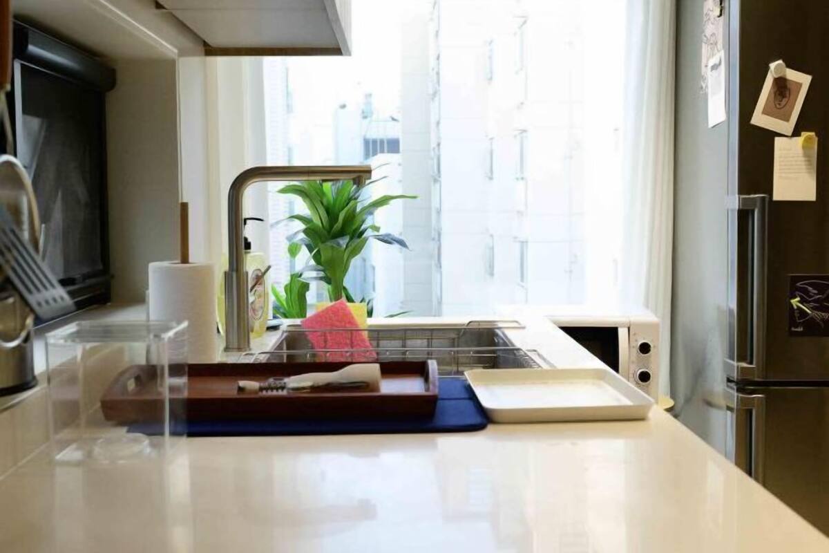 A modern kitchen with a stainless steel refrigerator, a microwave, and a sink with a window view.