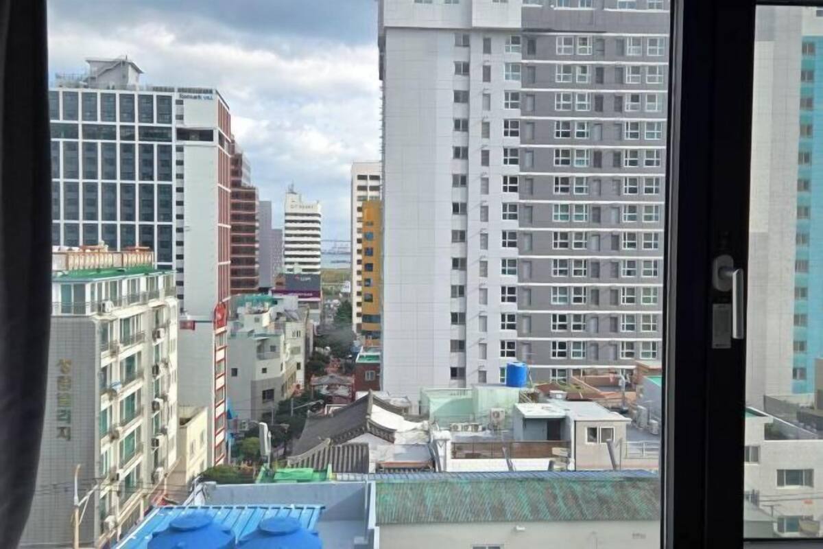 A cityscape with high-rise buildings, a mix of residential and commercial structures, and a view through a window with a door visible.