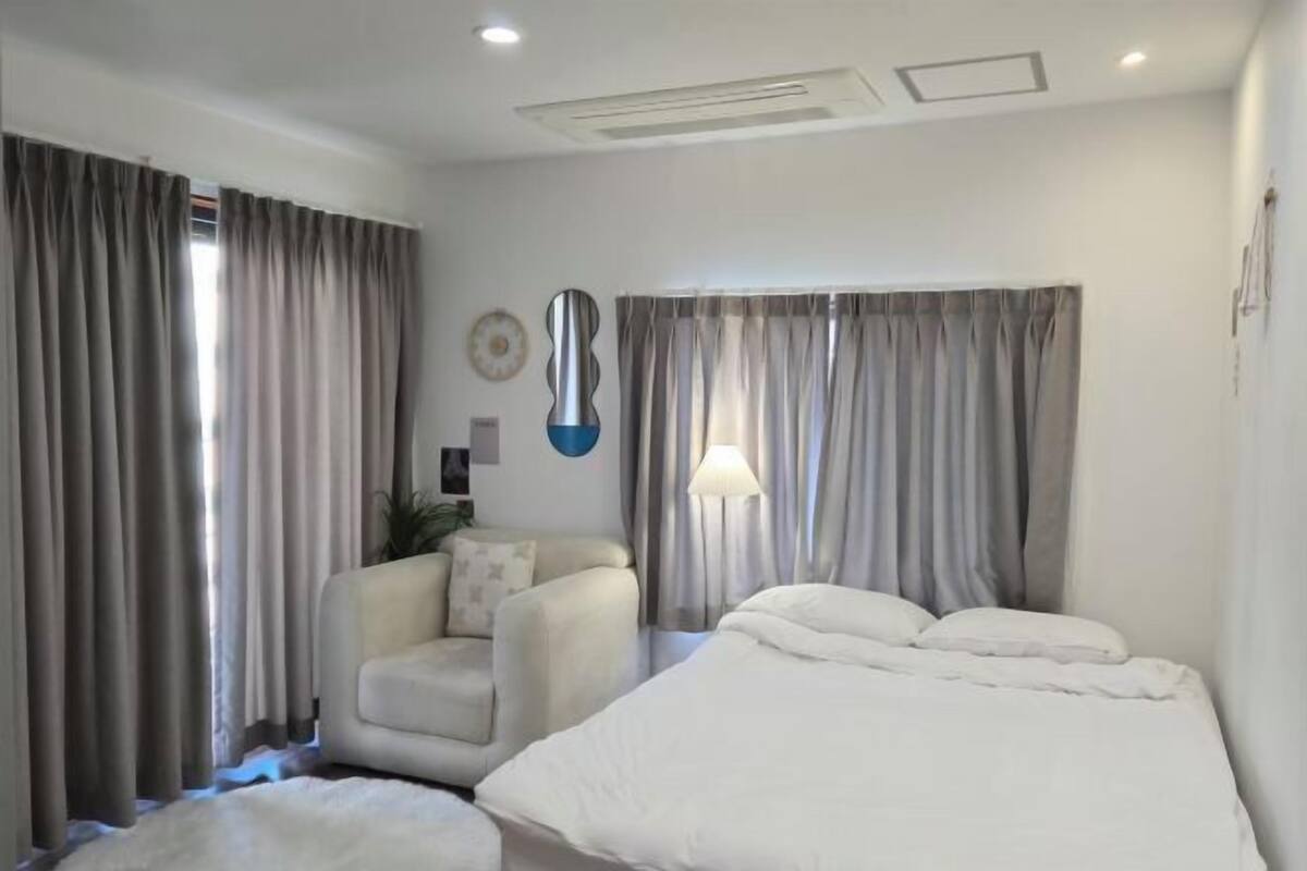 A hotel room with a bed, a chair, and curtains.
