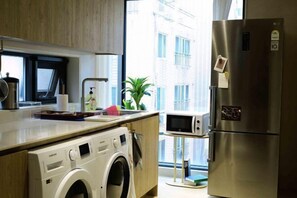A compact kitchen with a washing machine, a microwave, and a refrigerator.