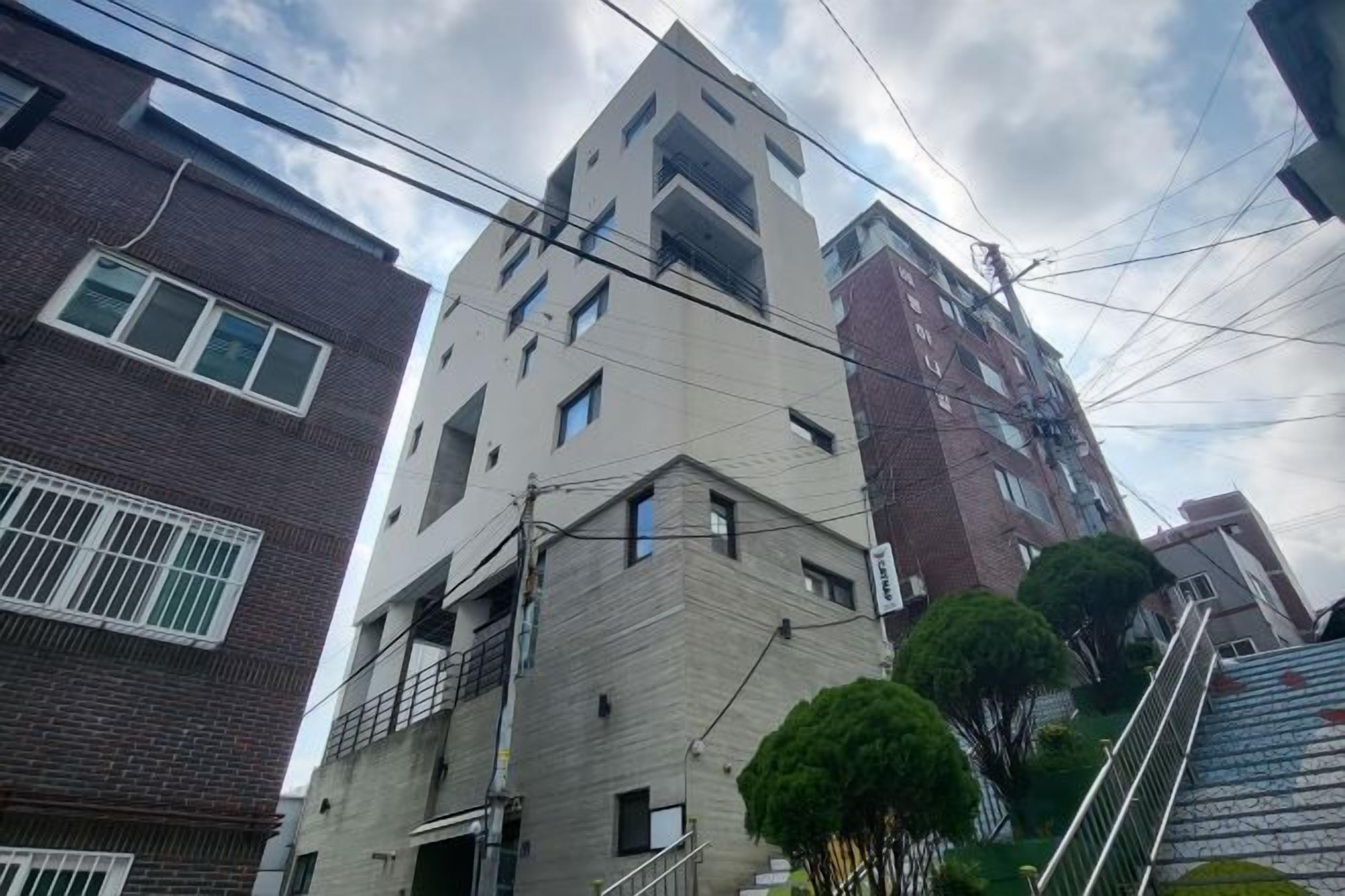 Um edifício de vários andares com design arquitetônico moderno, apresentando uma combinação de fachadas de tijolo e concreto, e uma escadaria que leva à entrada.