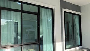 A modern interior with large windows, a staircase, and a clean, minimalist design. - Poome House By Zuzu (Hat Yai)