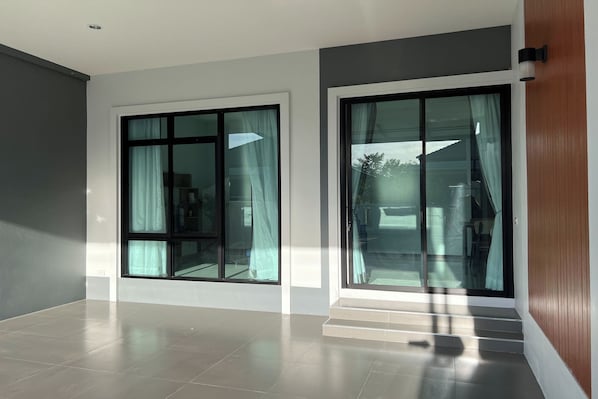 A modern room with large sliding glass doors, a tiled floor, and a wooden panel wall.