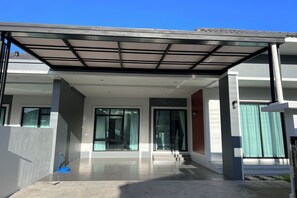 A modern house with a covered entrance, large windows, and a visible staircase. - Poome House By Zuzu (Hat Yai)