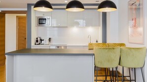 Eine moderne Küche mit Kochinsel, Edelstahlgeräten und einer Bar mit gelben Stühlen.