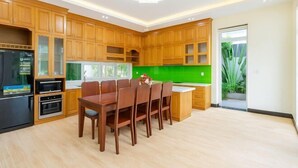 Une cuisine moderne avec des meubles en bois, une table à manger et un revêtement mural vert.