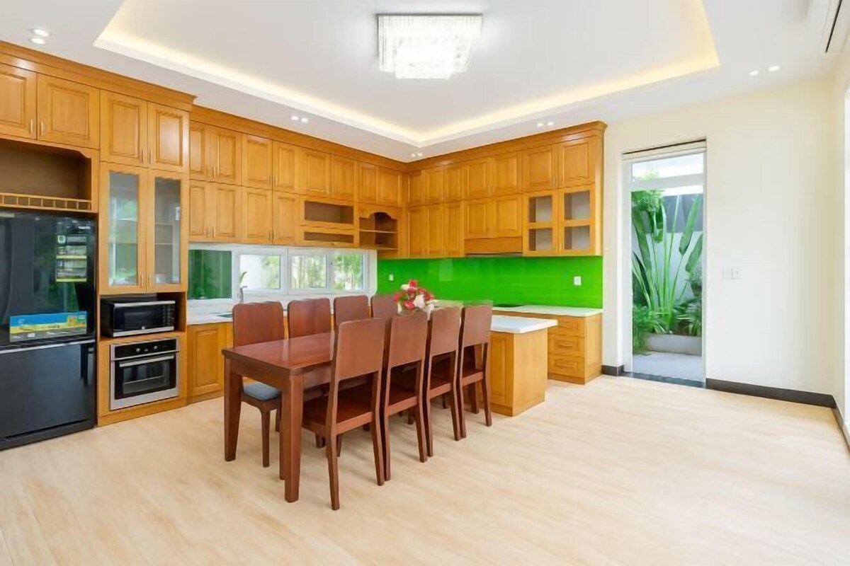 Eine moderne Küche mit Holzschränken, einem Esstisch und einer grünen Spritzschutzwand.