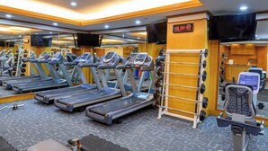 Un gimnasio con cintas de correr, máquinas de pesas y una pantalla de televisión.