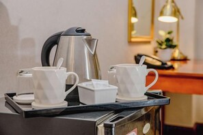 Una estación de café con hervidor, tazas y una bandeja.