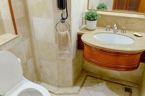 Ein Badezimmer mit Toilette, Waschbecken mit Spiegel, Handtuchhalter und einer Topfpflanze.