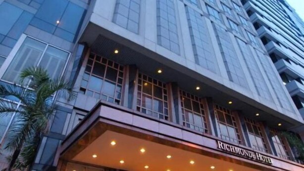 Un edificio de gran altura con fachada de vidrio, un llamativo letrero del 'Richmond Hotel' y un diseño arquitectónico moderno.