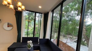 Een kamer met een groot raam met uitzicht op een rivier, een zwarte bank en een kleine tafel met een bloevas.