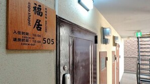 A hotel room entrance with a wooden sign indicating room number 505, check-in at 16:00, and check-out at 10:00. - Blessed Residence 505 (Osaka)