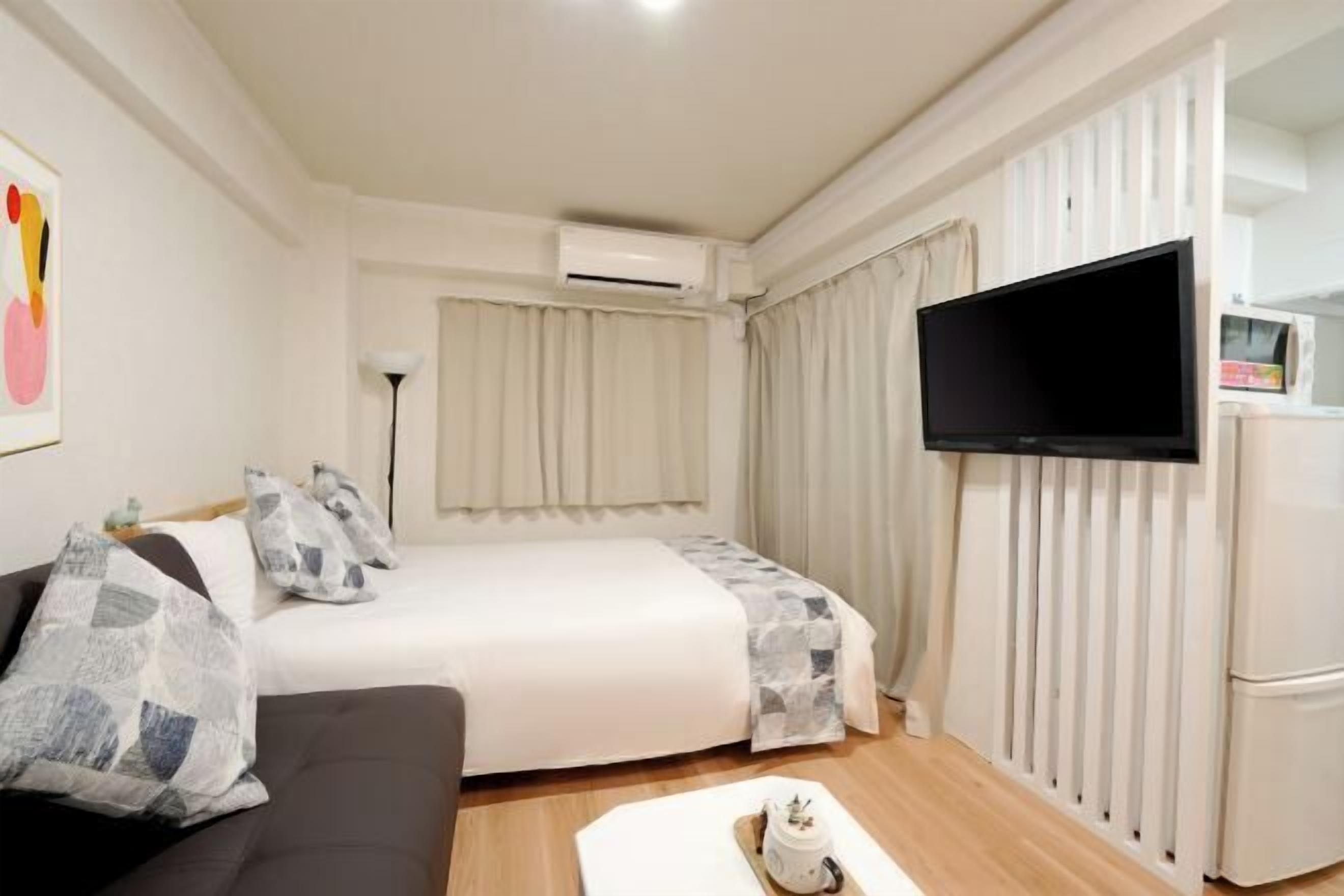 Une chambre d’hôtel équipée d’un lit, d’un canapé, d’une télévision à écran plat, d’un système de climatisation et d’un réfrigérateur.