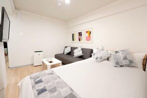 Une chambre à coucher avec un lit, un canapé, une petite table et un téléviseur.
