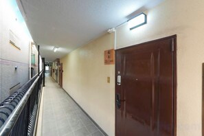 A corridor with doors on the right, a tiled floor, and a railing on the left. - Blessed Residence 505 (Osaka)