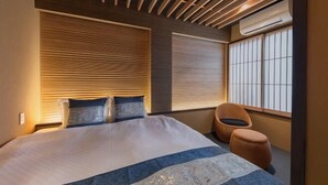 Una habitación de hotel moderna con una cama grande, dos mesitas de noche, una ventana con persianas y un techo con listones de madera.