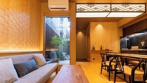 A modern interior with a sofa, wooden table, and bar seating. - Kyoran Akaritei (Kyoto)