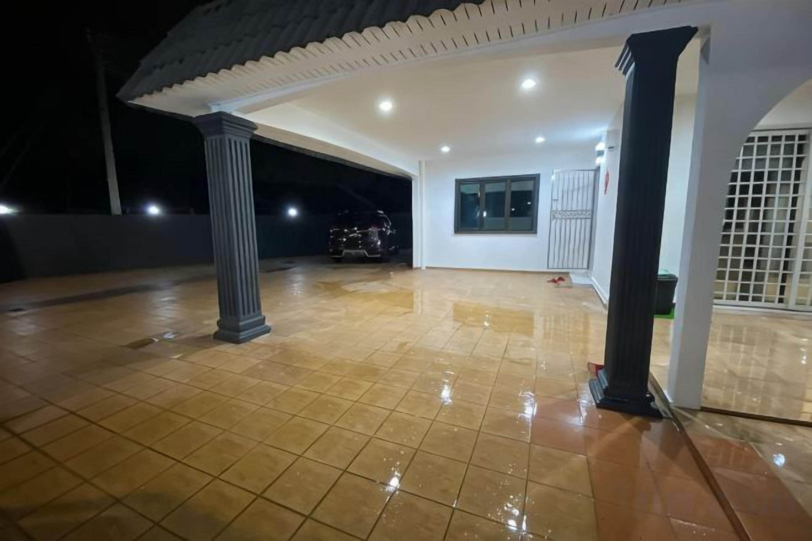 Un espacio exterior cubierto con suelo de baldosas, una columna y una puerta.