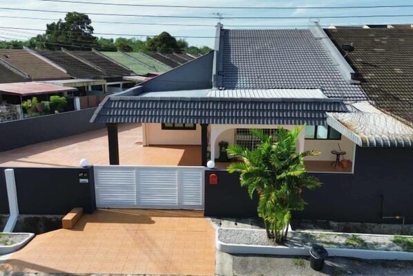 Un immeuble résidentiel doté d’un toit en tuiles, d’une entrée sécurisée par un portail et d’un petit jardin.