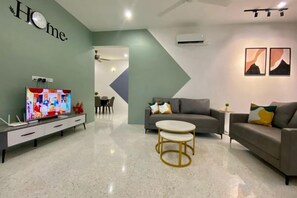 A modern living room with a flat-screen TV, a grey sofa, a round coffee table, and a dining area in the background. - 3BR/12pax LYL Ipoh town- homestay-5min to town (Ipoh)