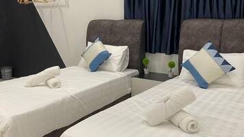 Habitación de hotel con dos camas, cada una con ropa blanca de cama y almohadas, una mesita con una planta y un cabecero oscuro.