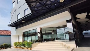 A modern building with a glass facade, a covered entrance, and a set of stairs leading to the entrance. - OPA Hotel Palembang (Palembang)
