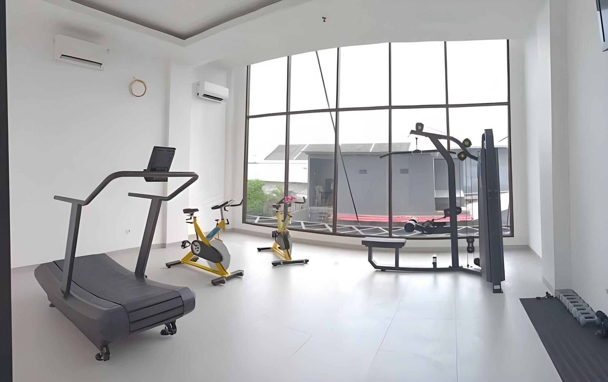 Une salle de sport moderne équipée de tapis de course, de vélos d’appartement et de matériel de musculation.