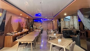 Un restaurante con una barra larga, varias mesas y un televisor en la pared.