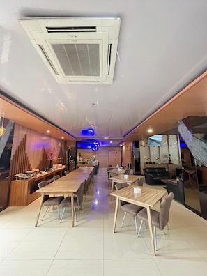A restaurant with a long counter, multiple tables, and a television mounted on the wall. - Opa Hotel Palembang (Palembang)