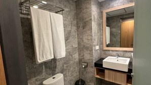 Un baño con inodoro, lavabo, espejo y toallero.