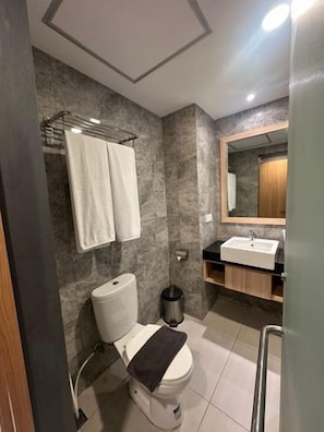 A bathroom with a toilet, sink, mirror, and towel rack. - Opa Hotel Palembang (Palembang)
