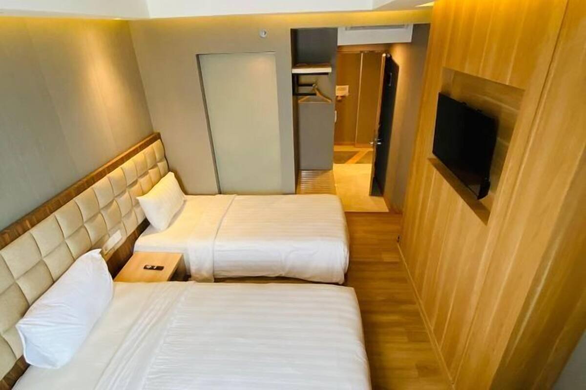 Une chambre d’hôtel avec deux lits, une télévision, une armoire et une petite table.