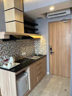 Eine kompakte Küche mit schwarzer Arbeitsplatte, Holzschränken, einer gefliesten Spritzschutzwand und einem integrierten Geschirrspüler.