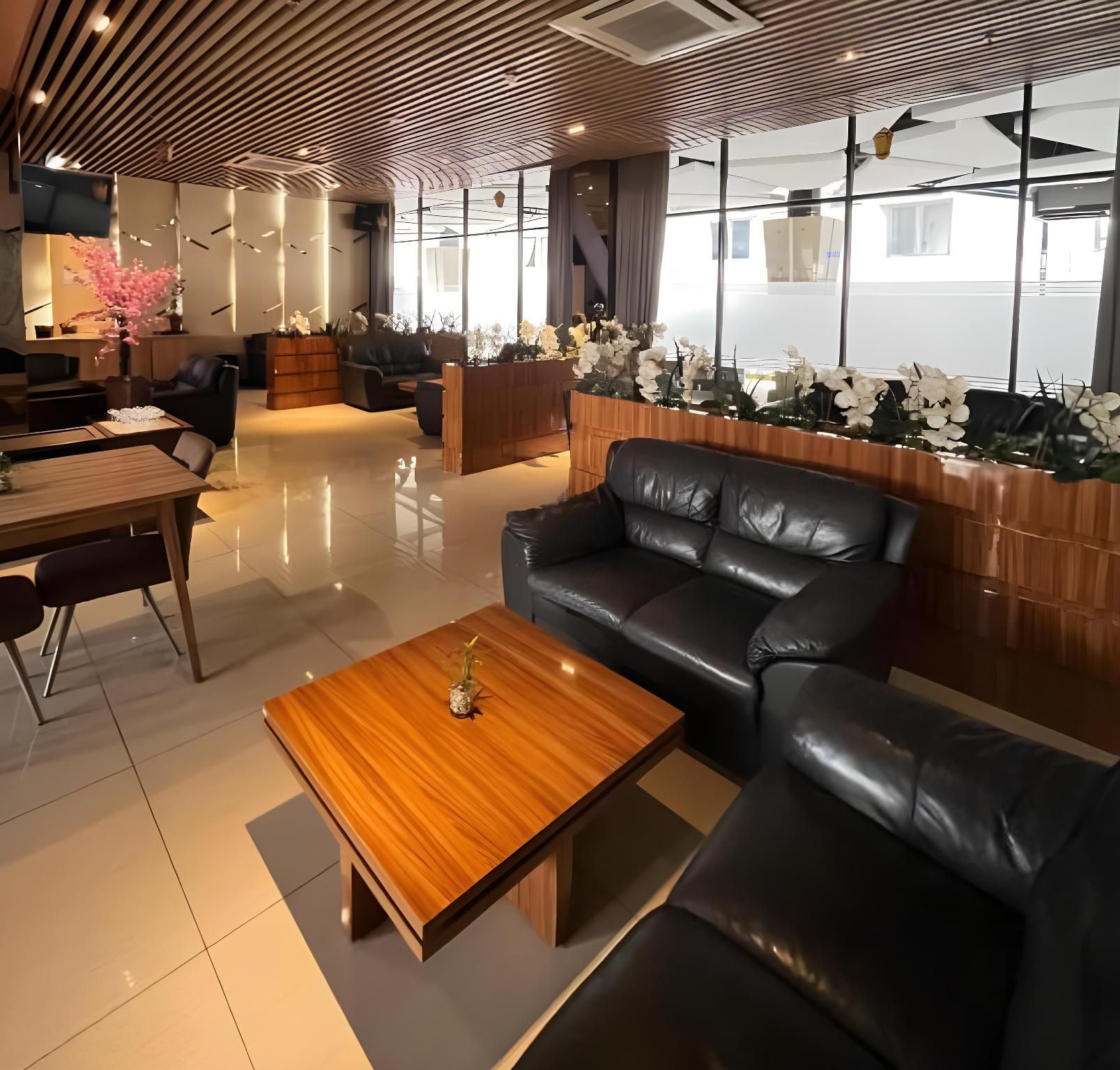 Un interior modern amb un sofà de pell, una taula de centre de fusta i una recepció decorada amb flors blanques.