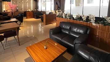Un interior modern amb un sofà de pell, una taula de centre de fusta i una recepció decorada amb flors blanques.