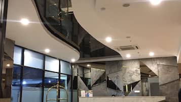 Un interior moderno con techo curvo, una escalera central y una recepción.