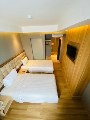 A hotel room with two beds, a wardrobe, a television, and a phone.