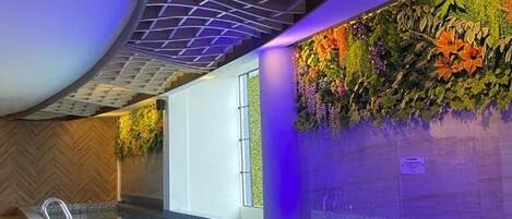A swimming pool with a curved ceiling and a wall decorated with plants.