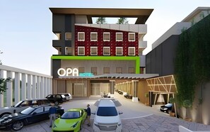A modern hotel with a prominent sign, multiple parking spaces, and a variety of vehicles. - Opa Hotel Palembang (Palembang)