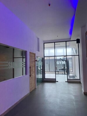 A hallway with a glass door leading to a gym area. - Opa Hotel Palembang (Palembang)