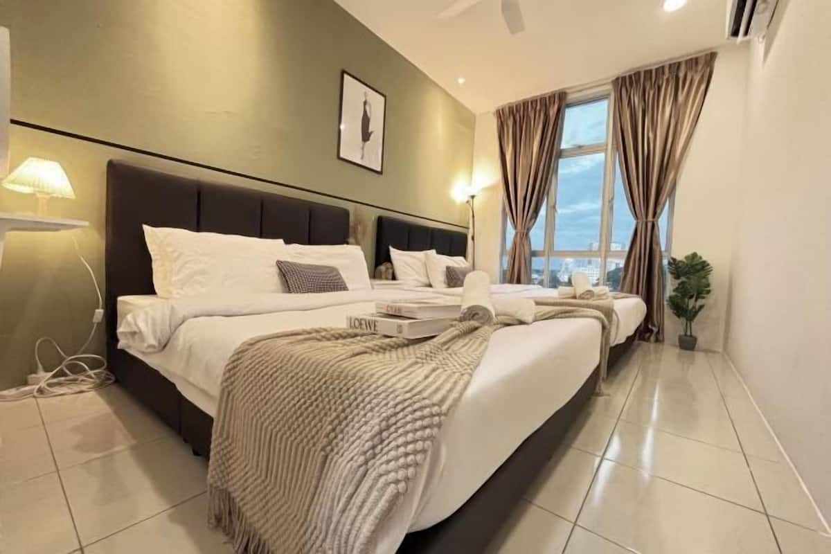 A modern hotel room with a large bed, a bedside lamp, a window with curtains, and a city view.