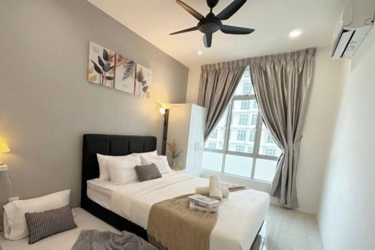 A hotel room with a bed, bedside table, lamp, and a window with curtains.
