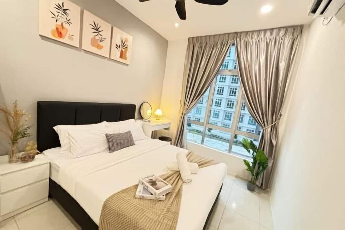 A neatly arranged bedroom with a bed, bedside table, lamp, and window with curtains.