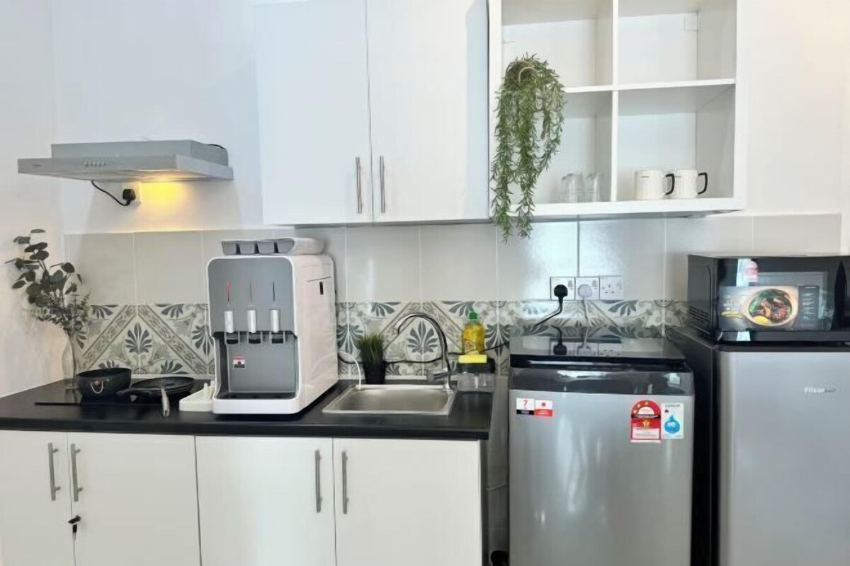 Una cocina con armarios blancos, cafetera, microondas y refrigerador.