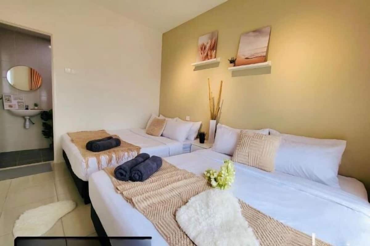 A hotel room with two beds, a small bathroom, and artwork on the walls.