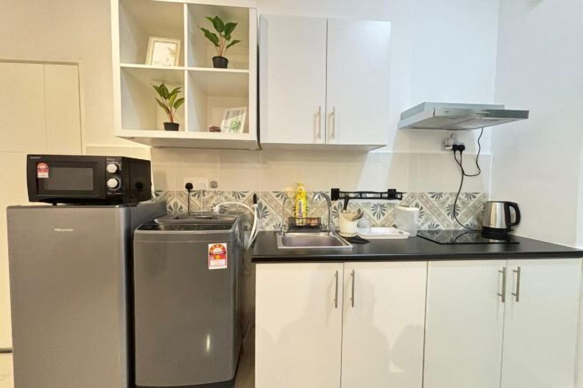 Cocina compacta con microondas, refrigerador y un área pequeña para el lavamanos.