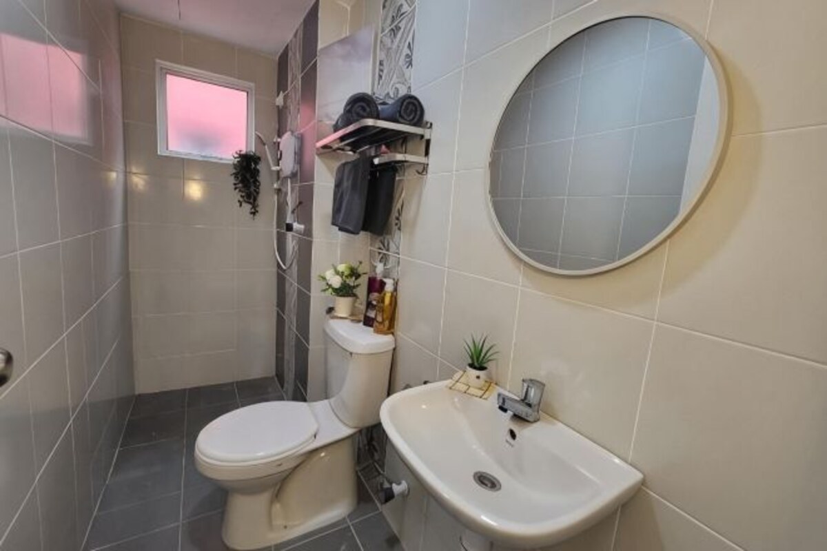 Un baño con inodoro, lavamanos y un espejo redondo.