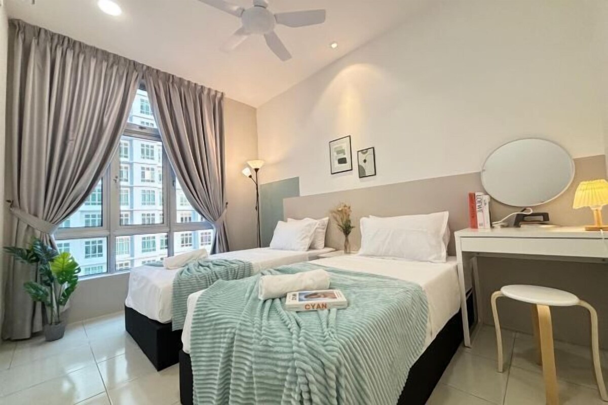 Habitación de hotel con dos camas, un escritorio, una silla, un ventilador de techo y una ventana con cortinas.
