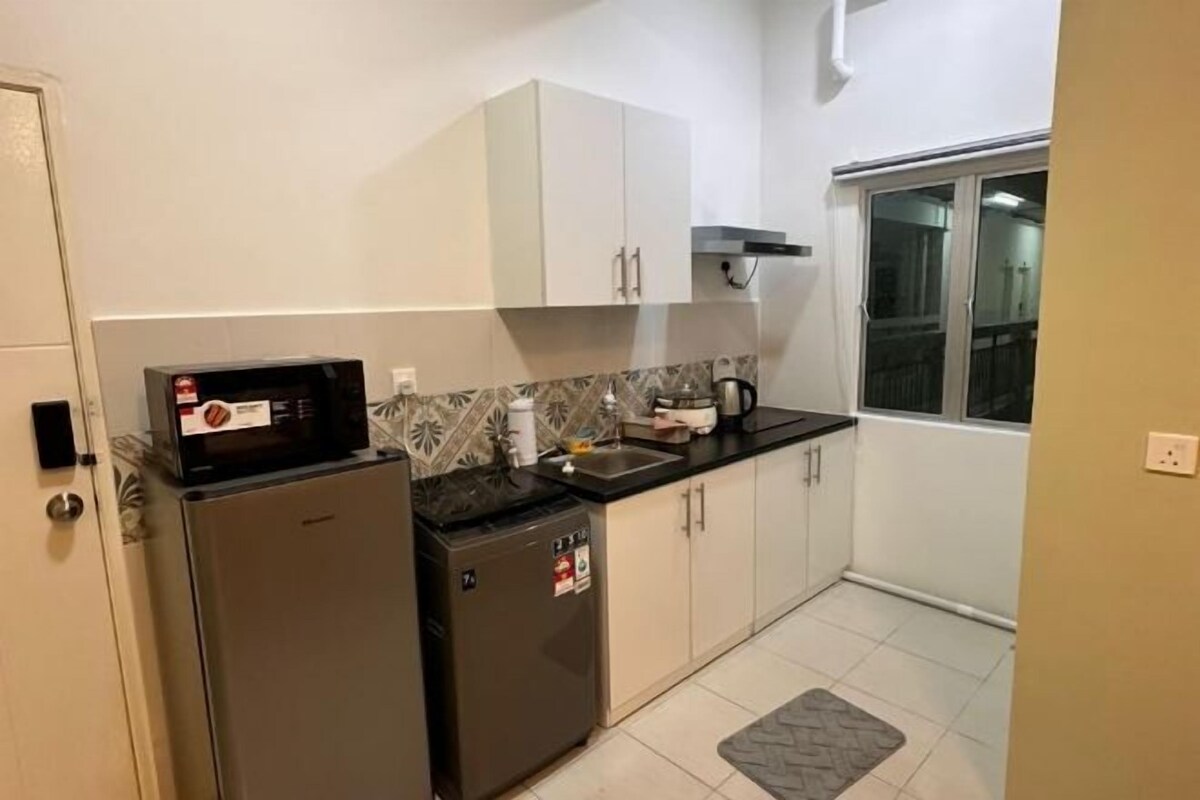 Una cucina compatta con frigorifero, forno a microonde e una piccola macchina per il caffè sul piano di lavoro.